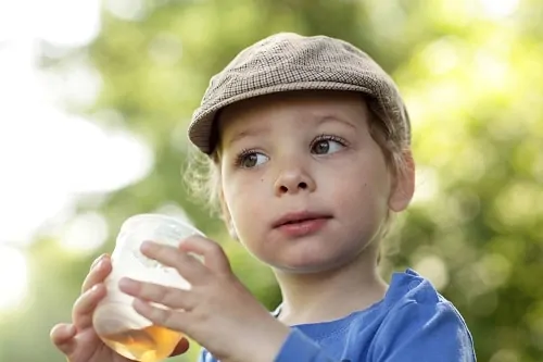 toddler with hat drinking juice