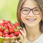 girl with braces holding strawberries