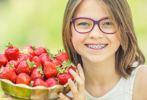 girl with braces holding strawberries